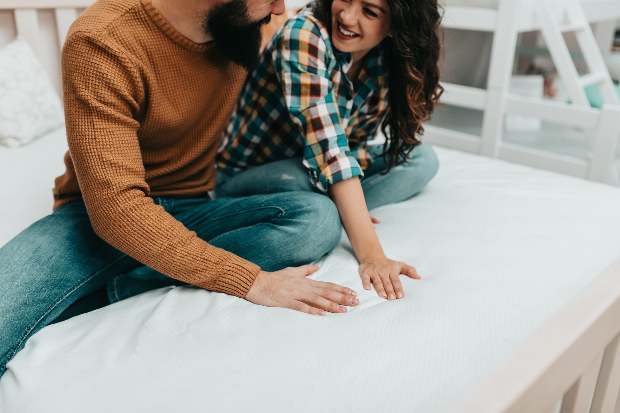 Young happy couple testing out a new mattress with their hands.