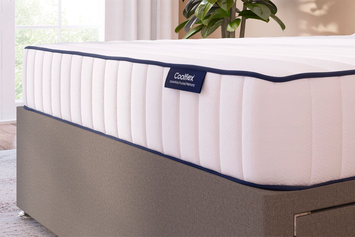 Close up of the side of the Coolflex essential hybrid mattress with a blue tag of the brand logo. On a grey divan base.