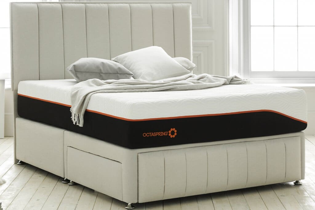In a white bedroom, a Dormeo Octaspring Tribrid Latex Hybrid mattress rests on top of a 2 drawer divan base