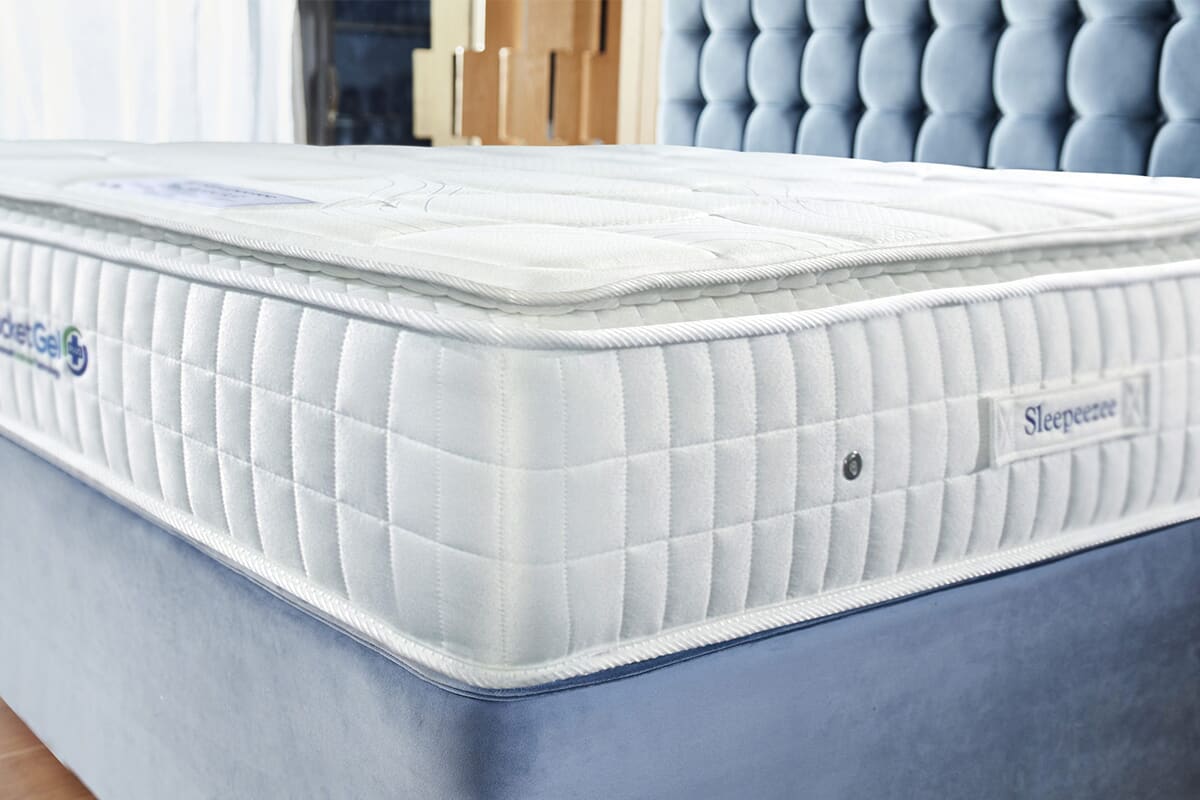 Close up of the sleepeezee pocket gel mattress on a blue upholstered divan bed.