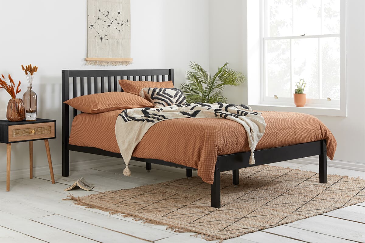 Lifestyle image of the Birlea Nova Black Bed Frame with orange sheets.