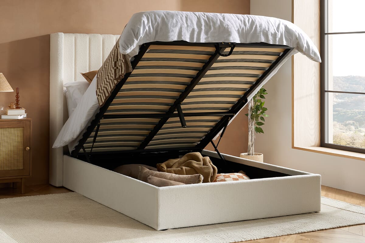 White ottoman bed open to reveal storage area in a natural-toned bedroom.
