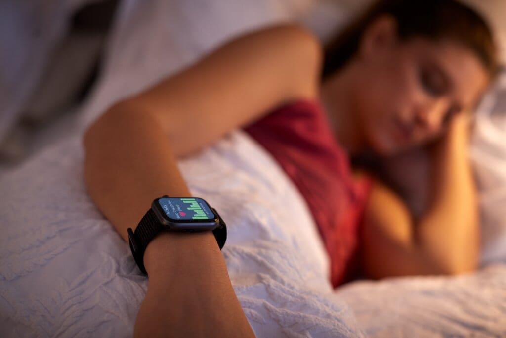 Woman Sleeping In Bed With Focus On Smart Watch She Is Wearing, Depicting Use Of Artificial Intelligence.