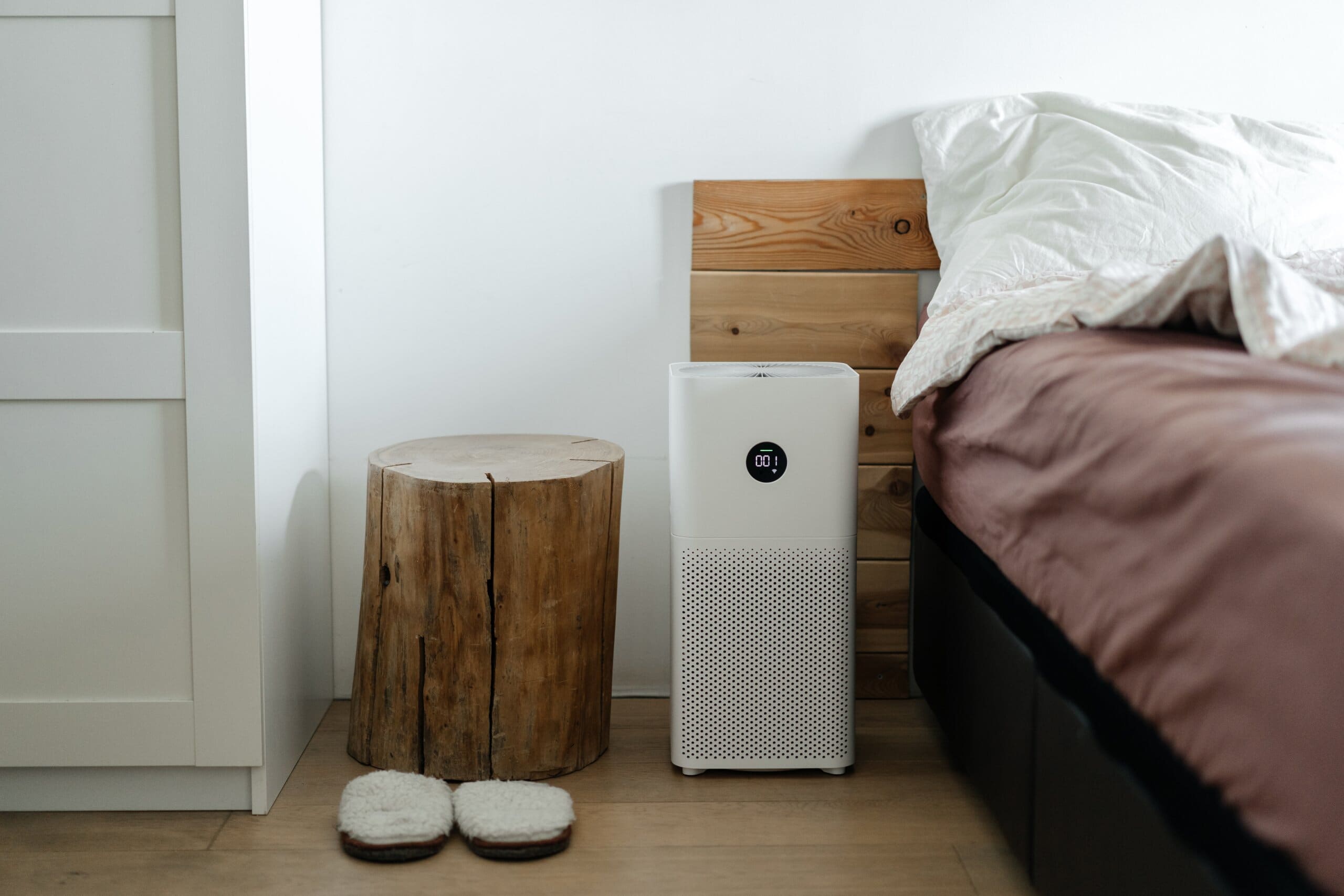 Large air purifier placed next to the side of a bed.