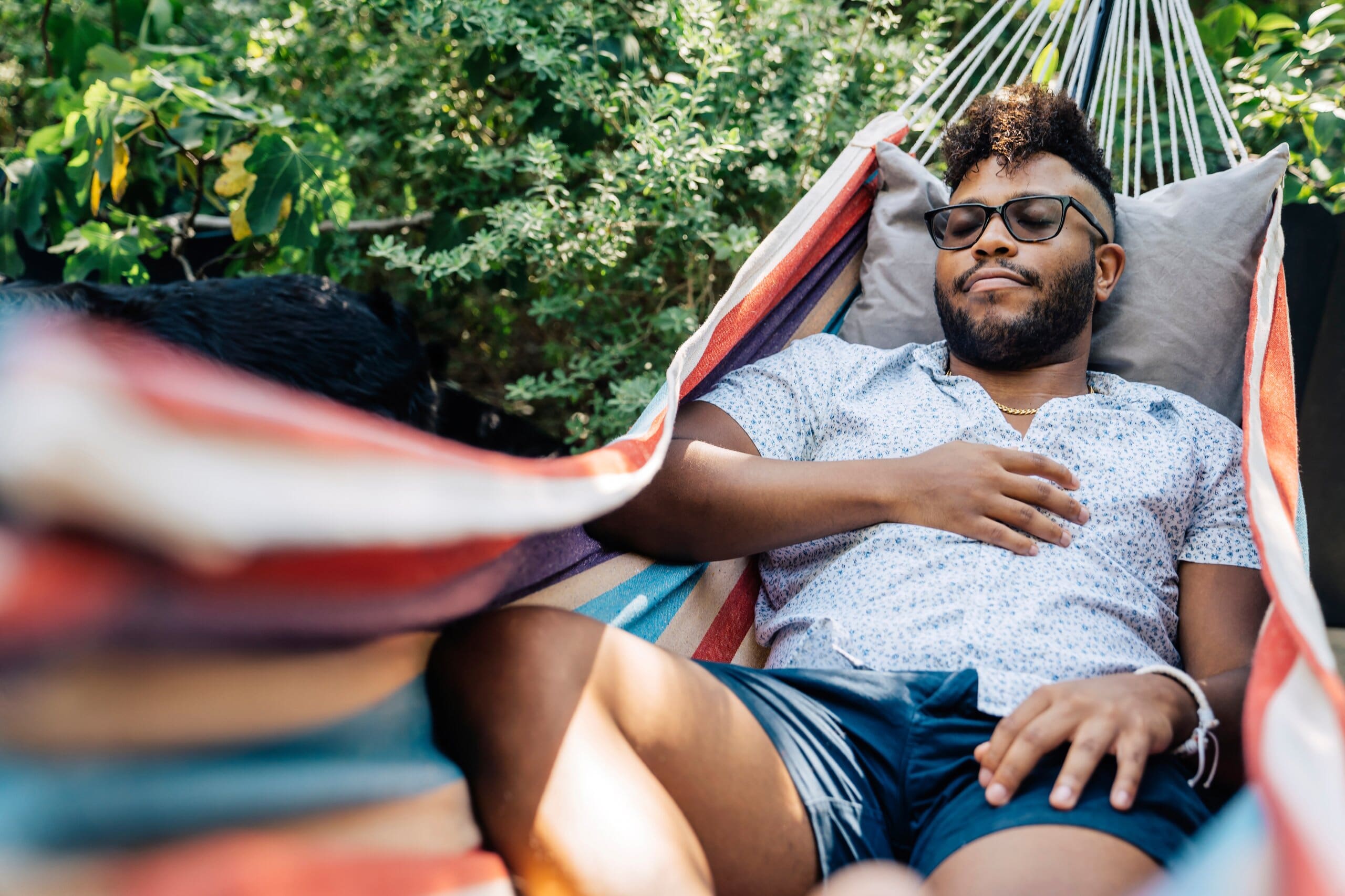 Man napping outside in a hammock.