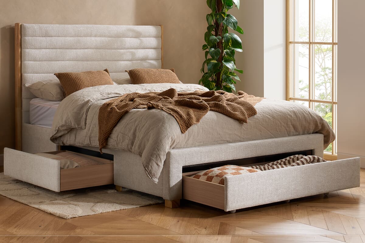 Bed with drawers at the sides and bottom opened to show bedding. The bed is dressed with Earth-toned bedding.