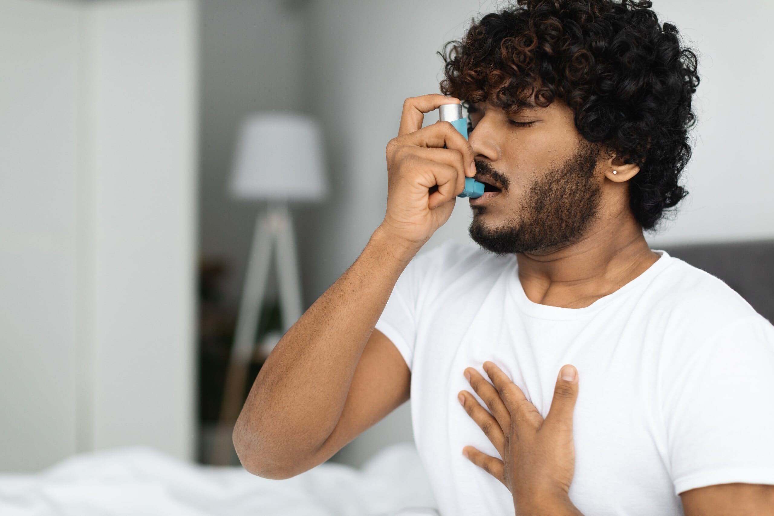 Man with asthma using an inhaler.