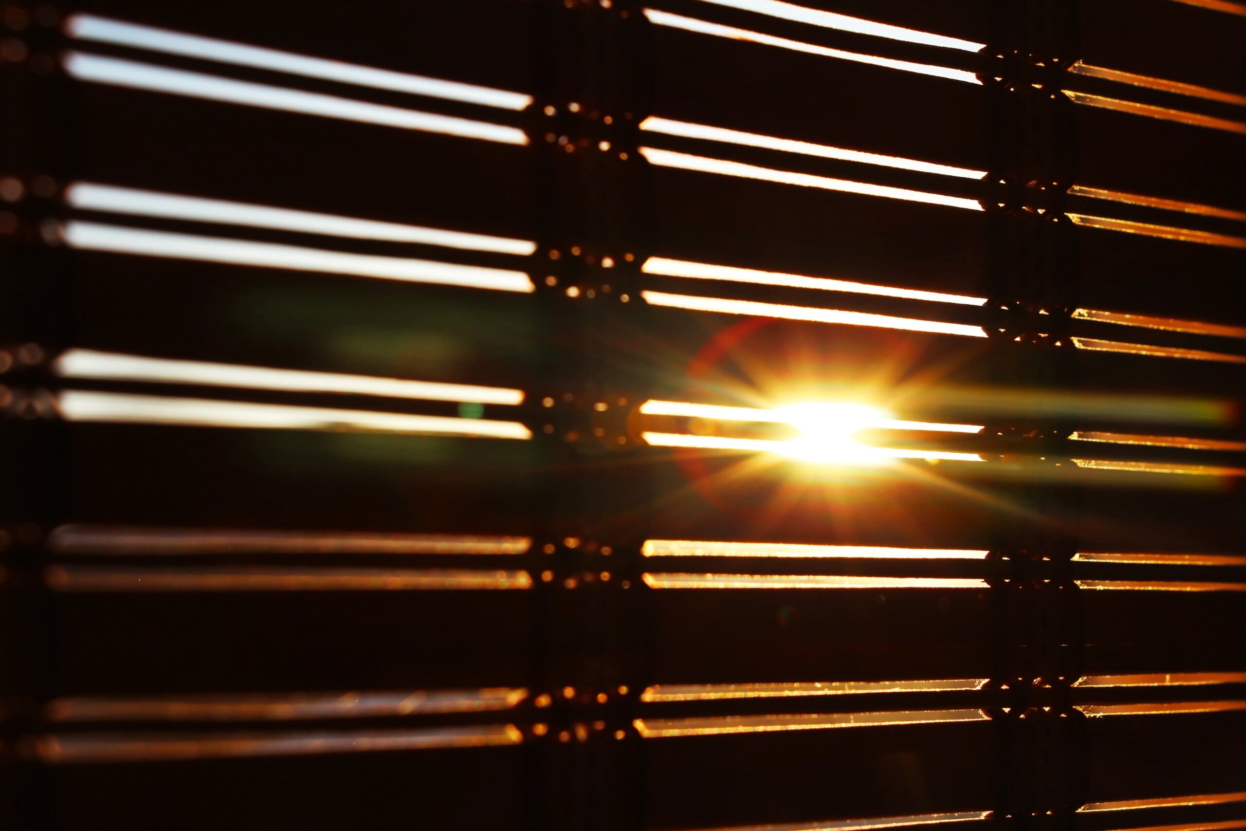 Rays of sunshine peaking through bedroom blinds.