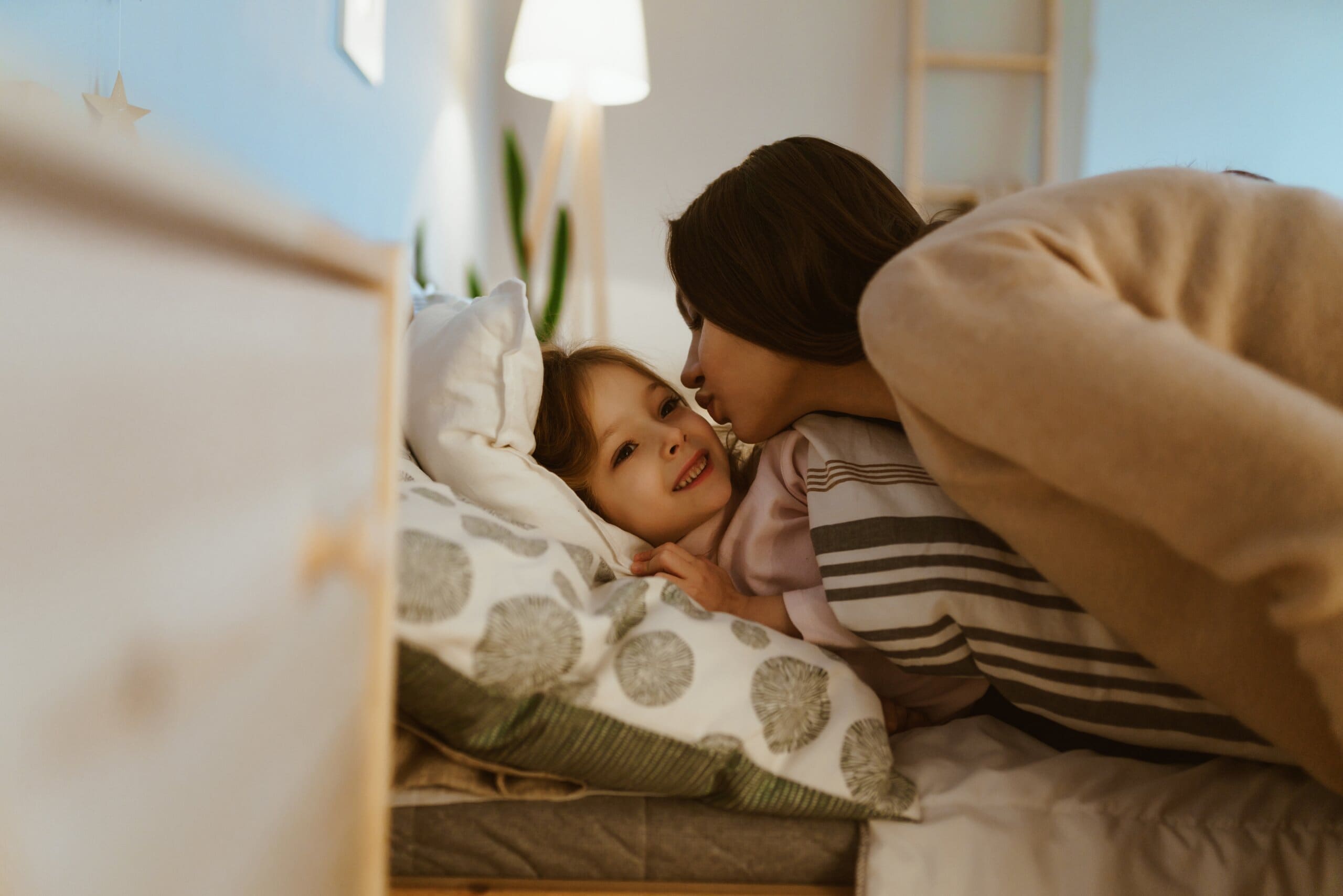 Mother kissing her daughter goodnight.