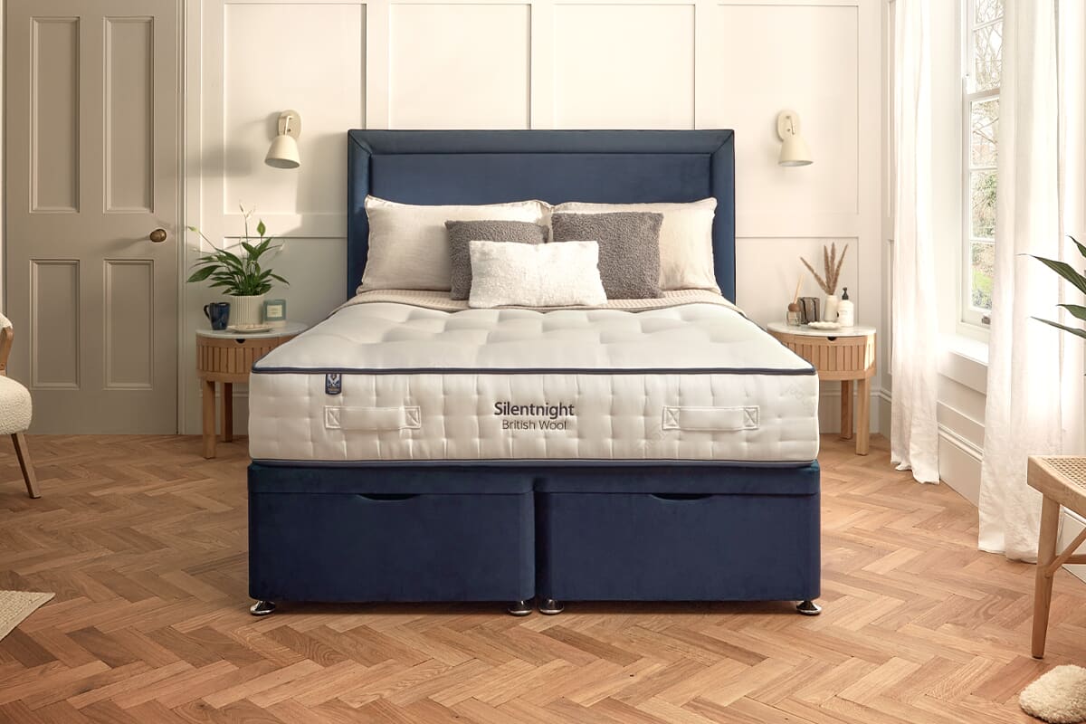 The Silentnight British Wool 1600 Pocket mattress on a dark blue divan bed in a light bedroom.