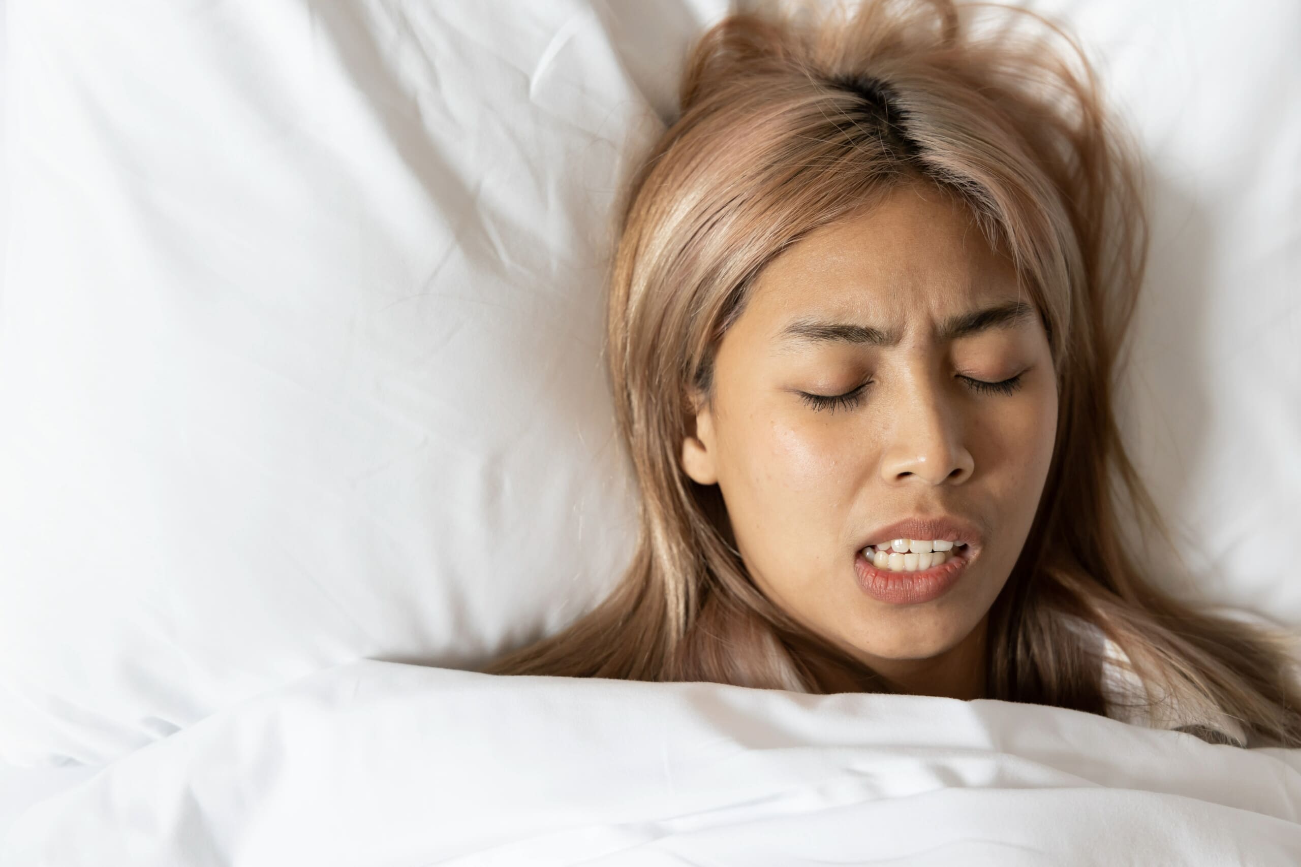 Woman experiencing grinding teeth in sleep.