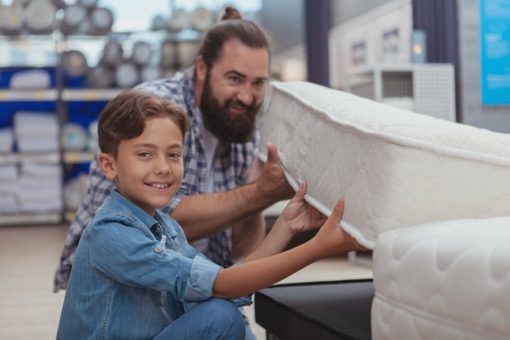 Young boy and man choosing a budget mattress in a shop.