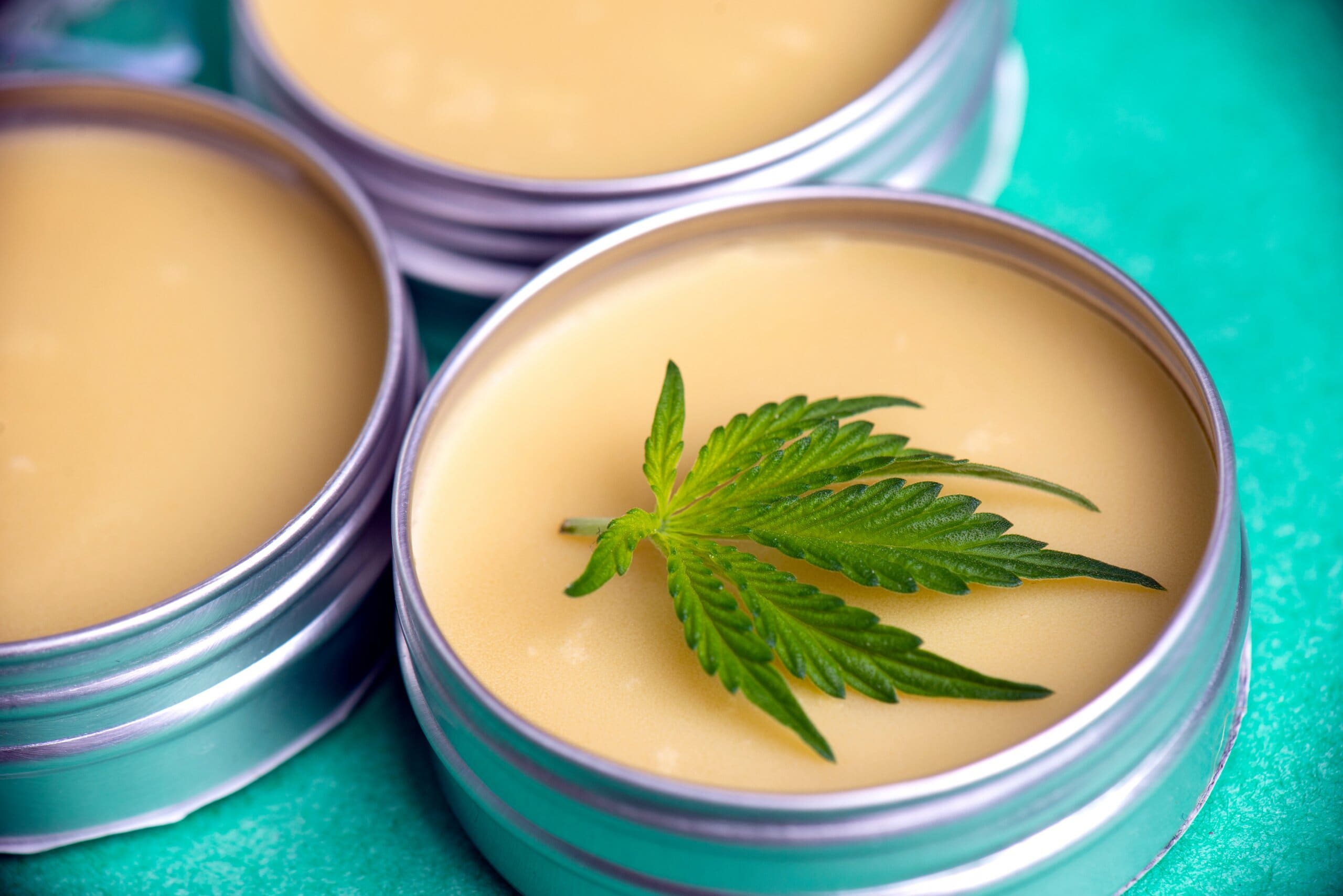 Silver tins of yellow balm with a hemp leaf on top.