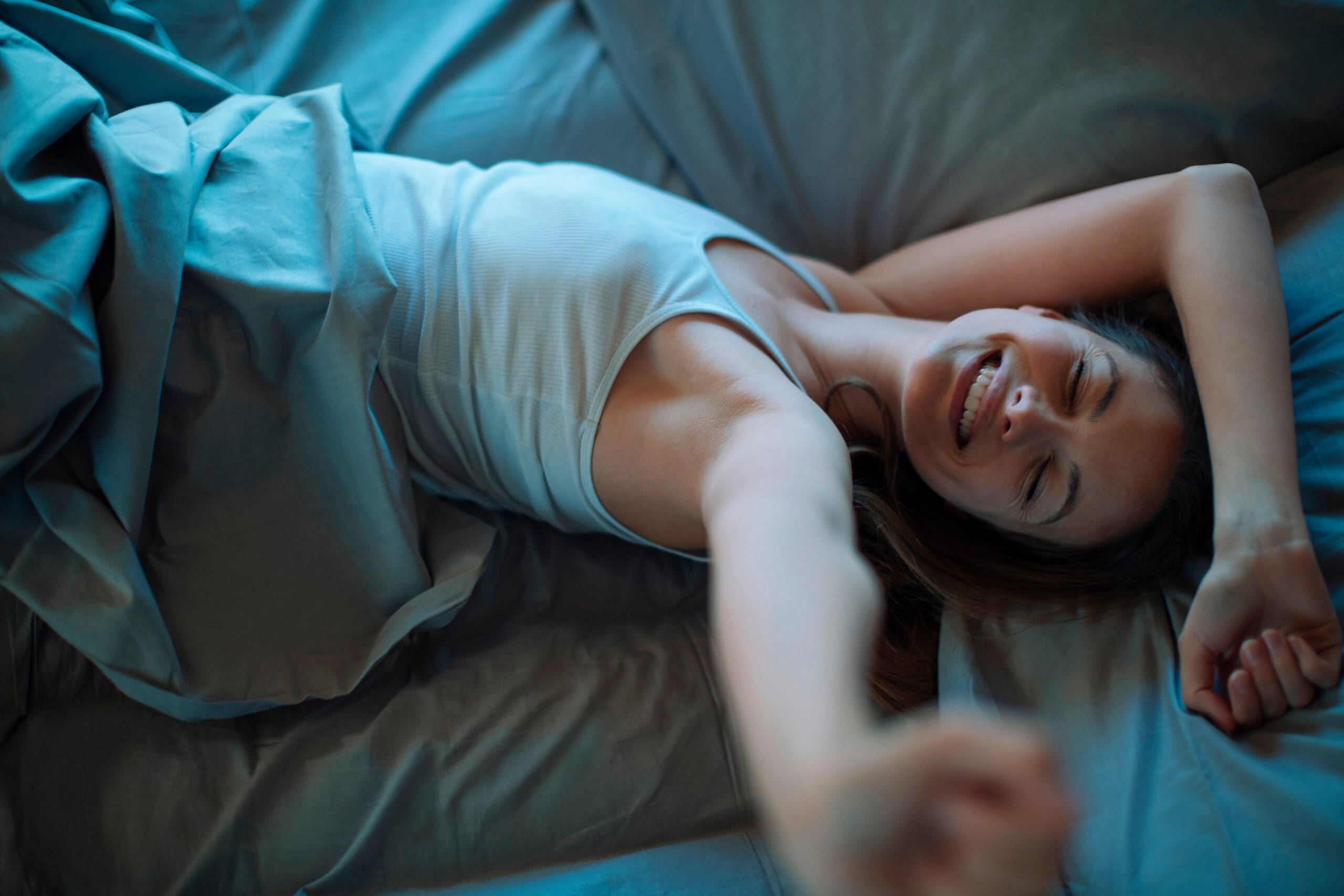 Young woman stretching waking up on a cool memory foam bed.