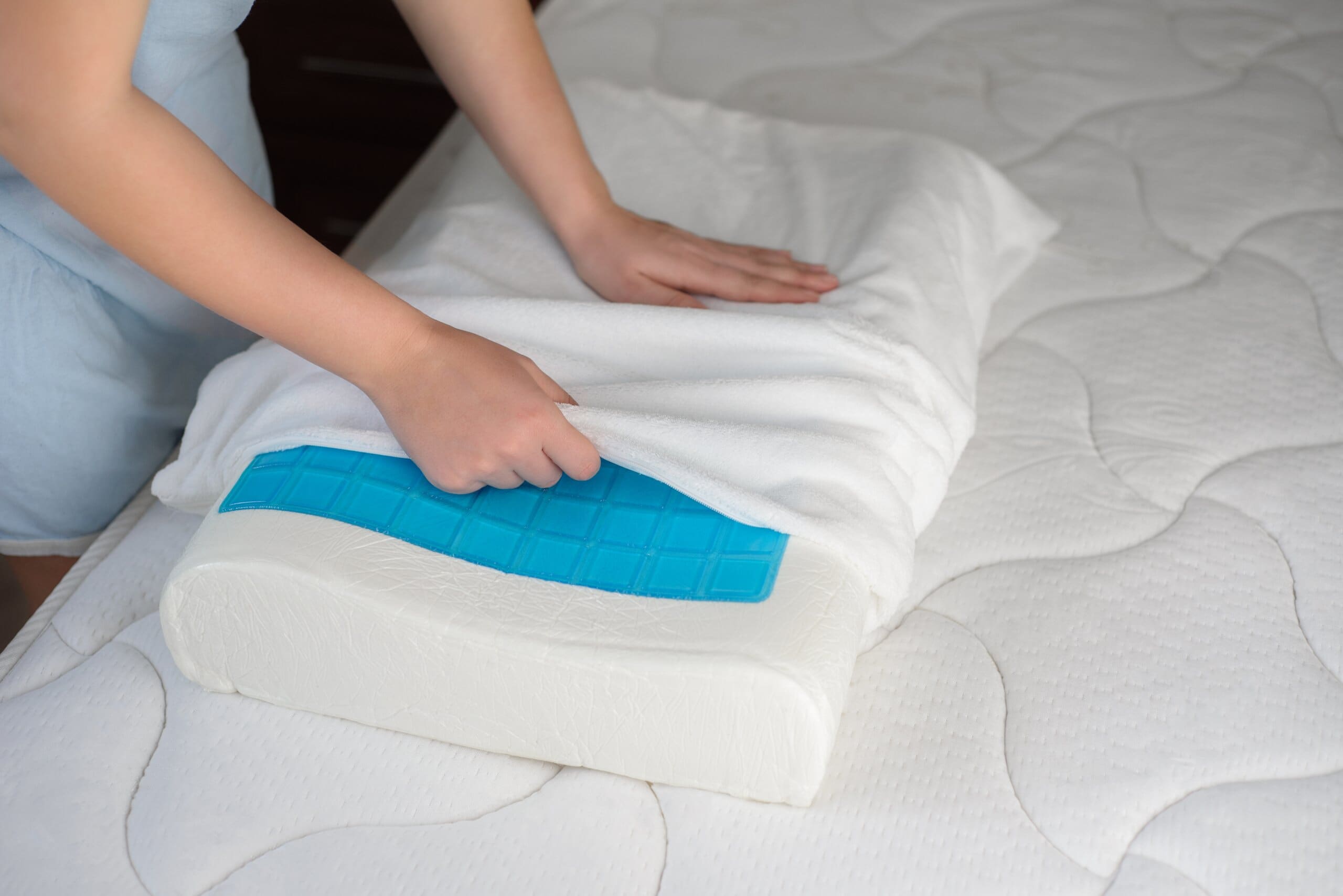 Woman's hands putting a cover on a cooling gel memory foam pillow.