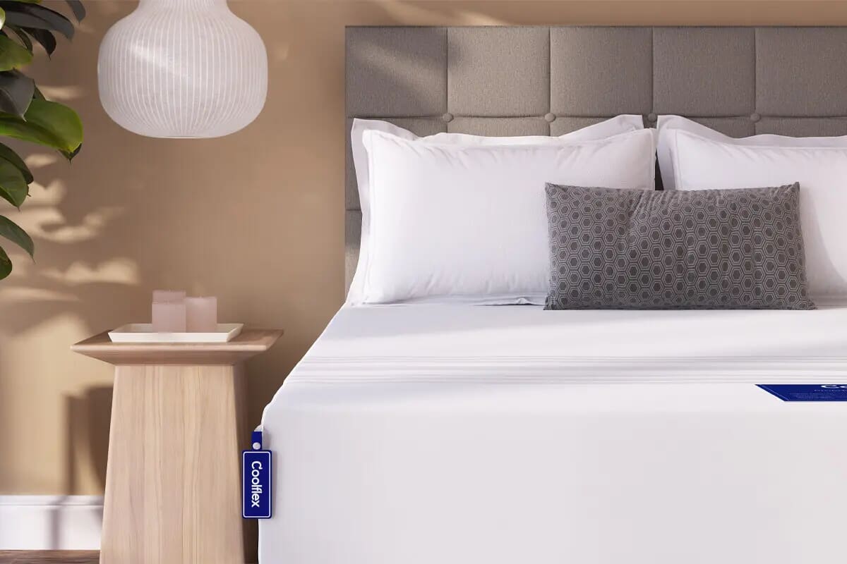 Corner of the coolflex mattress on a divan bed, with a bedside table to the side.