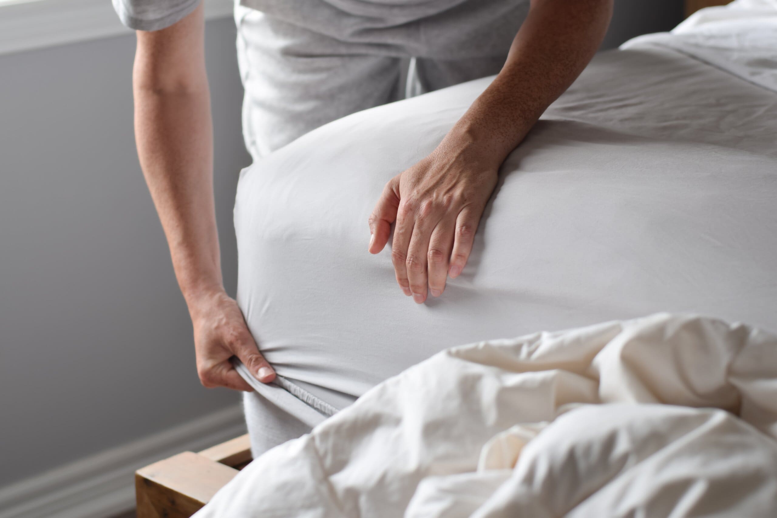 Cropped image of someone putting a deep fitted sheet on a thick mattress.