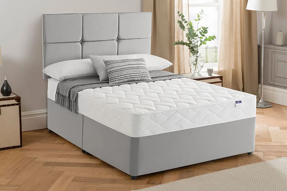 Image of a white mattress on a light grey divan bed.