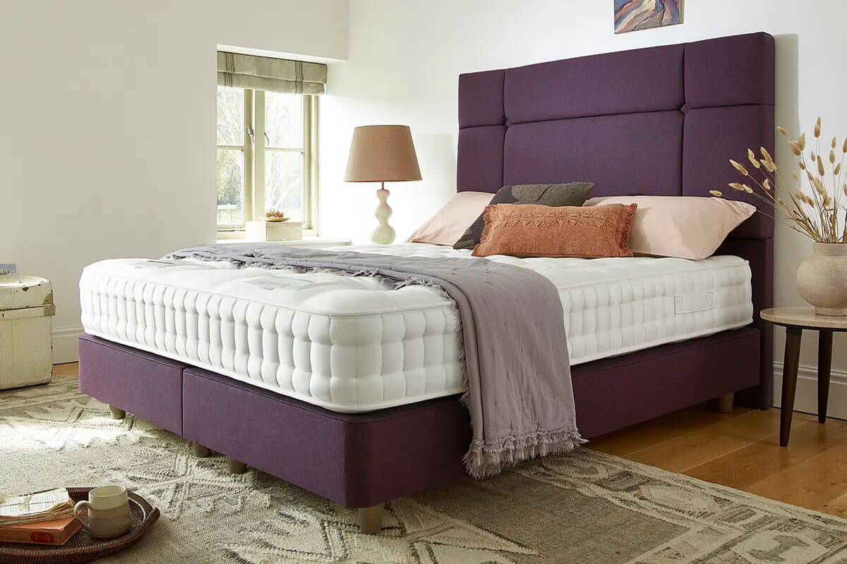 Image of the luxury Harrison Spinks Ely mattress on a dark purple divan bed.