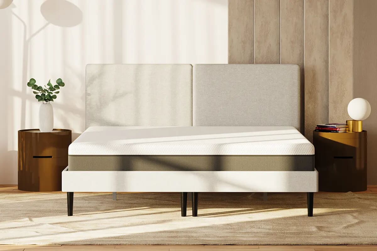 Front on full image of Emma hybrid mattress with two rounded bedside tables on either side.