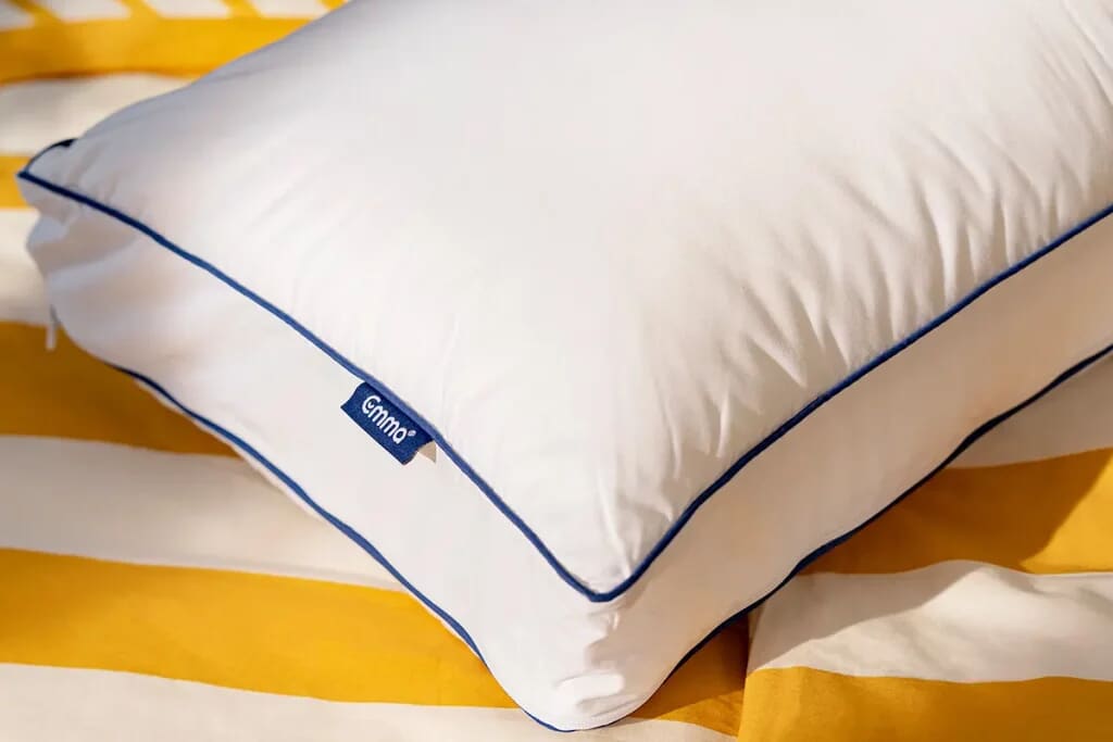 Image of the Emma Premium Pillow on a white and yellow striped sheet.