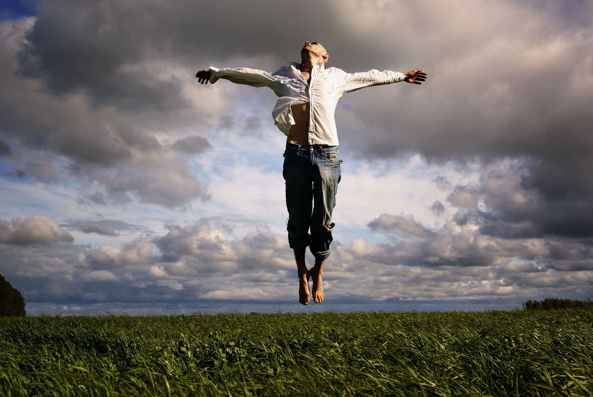 Man in field lifting off the ground as he begins to fly.