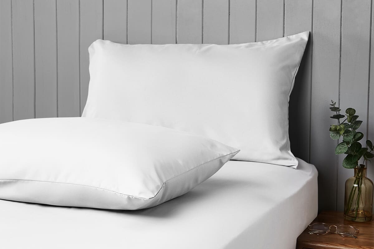 White pillows on a white bed sheet covered bed. Cooling bedding imagery.