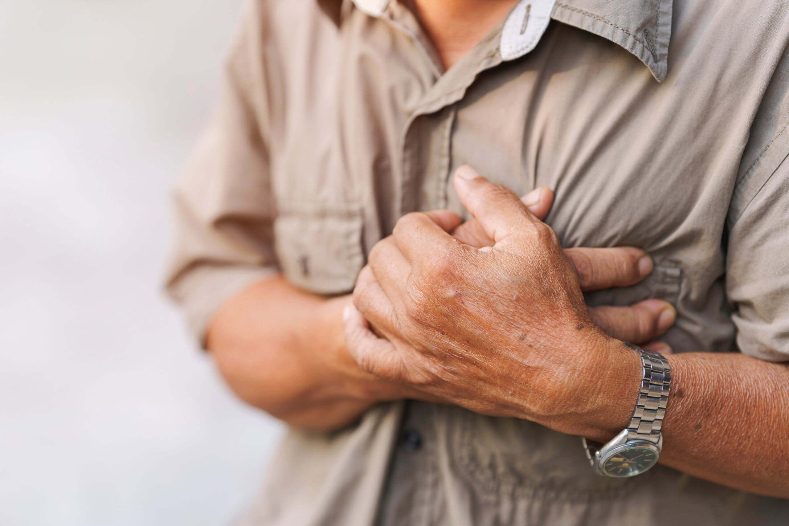 Close up of man's hands clutching his chest.