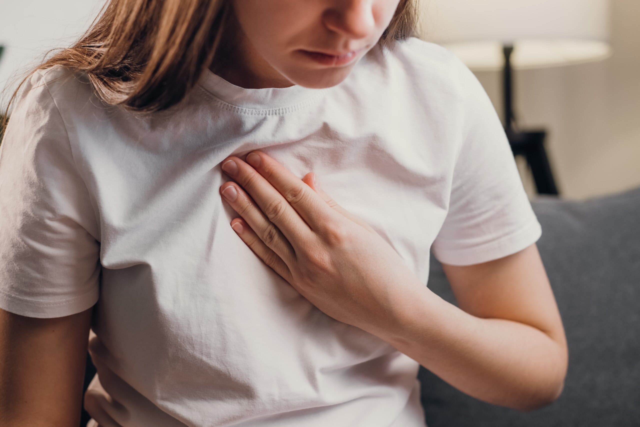 Young woman clutching her chest in pain.
