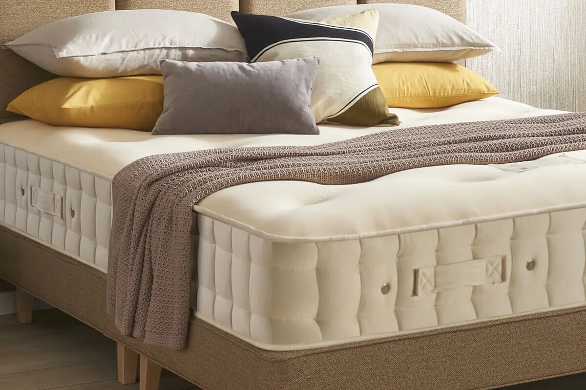 Close up of the corner of Hypnos mattress with pillow and a beige divan bed.