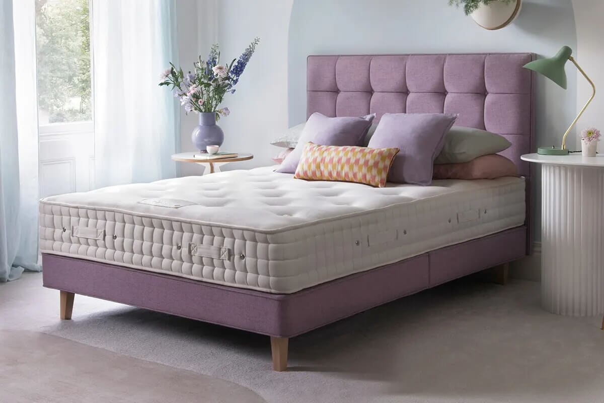 Image of luxury Hypnos mattress on a pink divan bed with colourful decor.