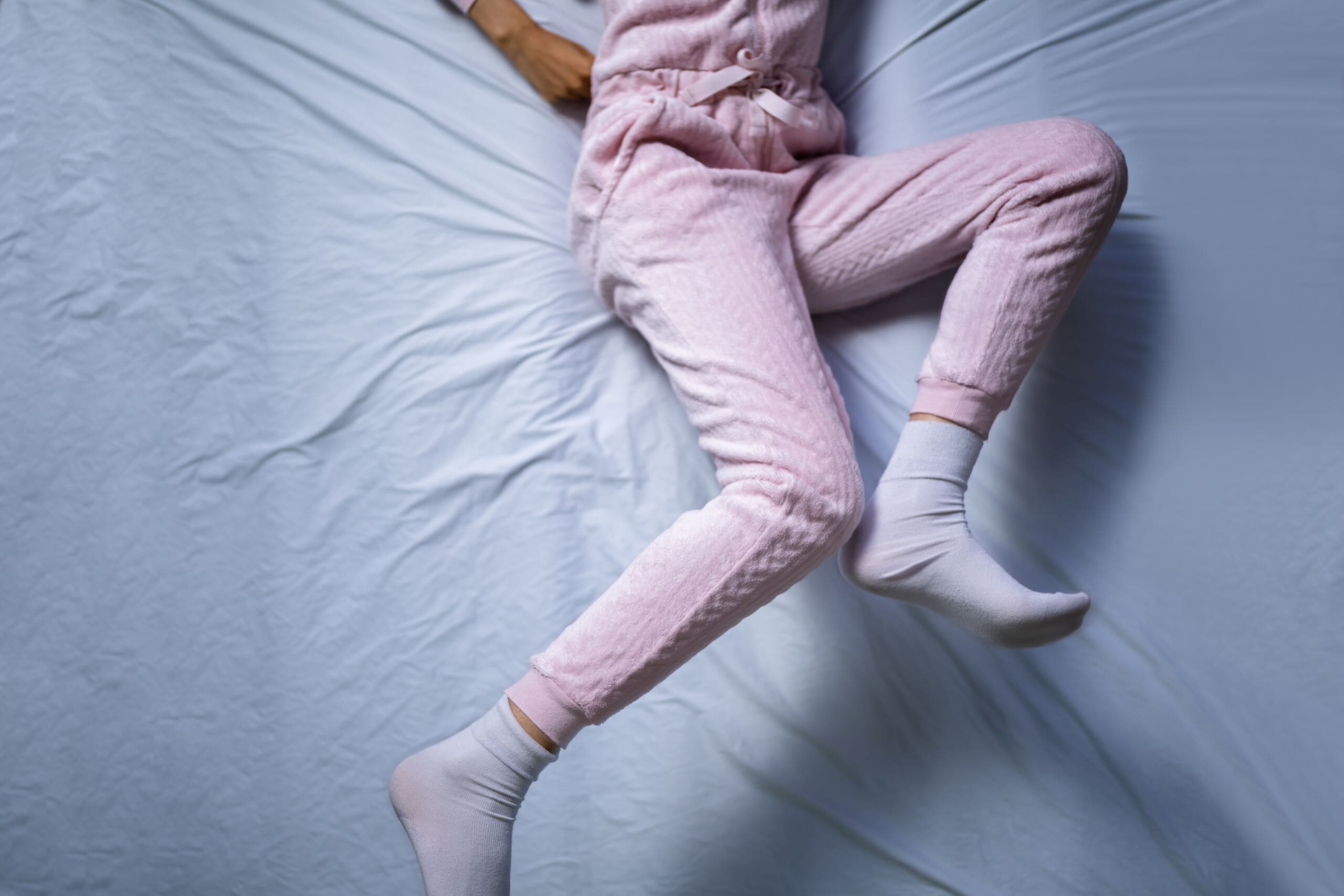 Woman's legs in bed kicking.