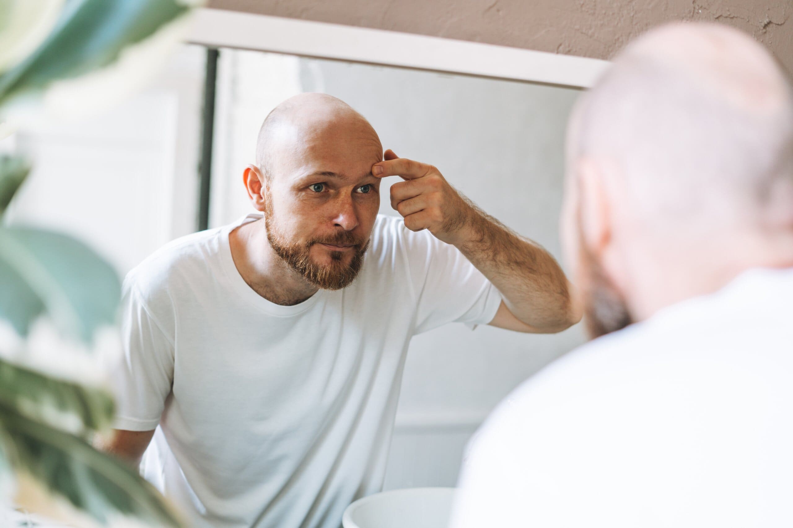 Man looking in the mirror inspecting his skin.