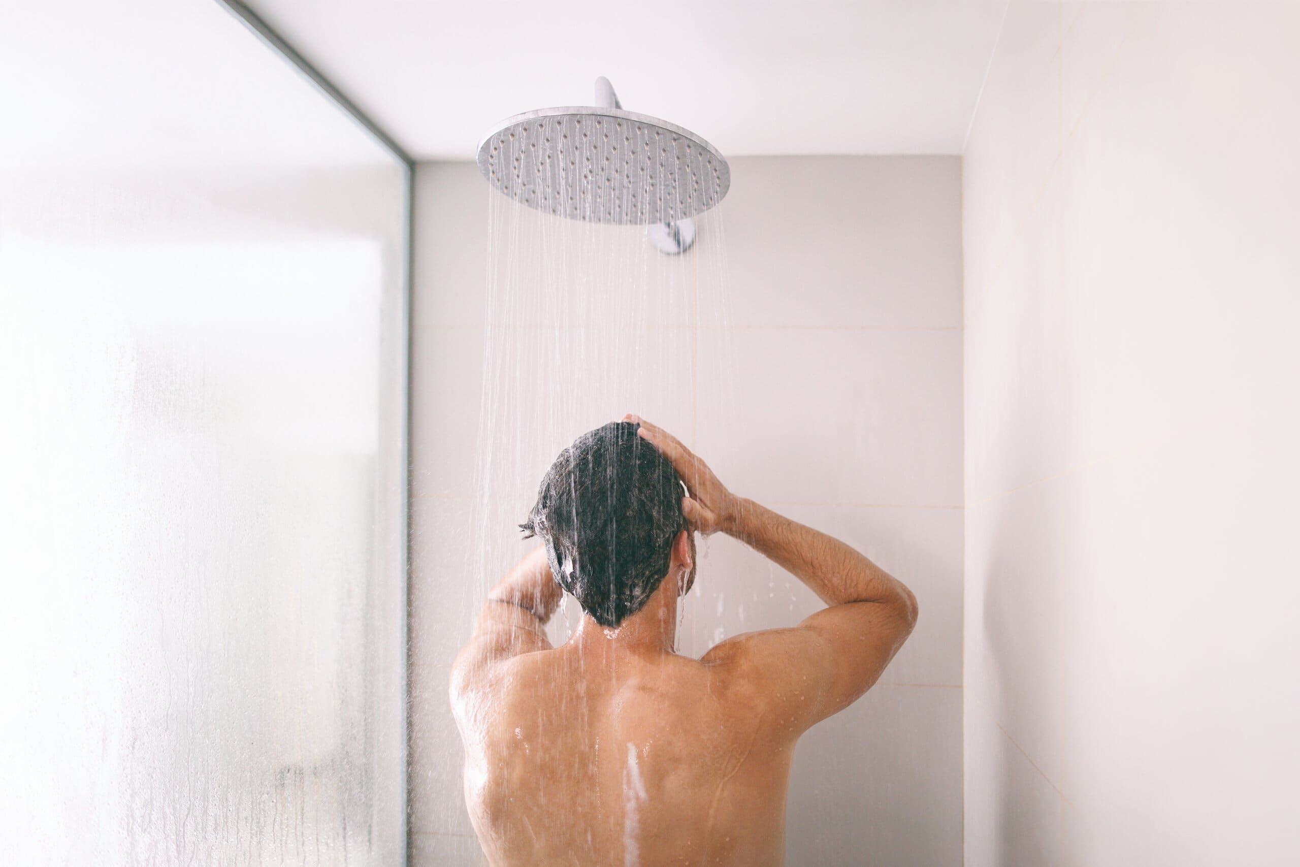 Back view of a man taking a shower.