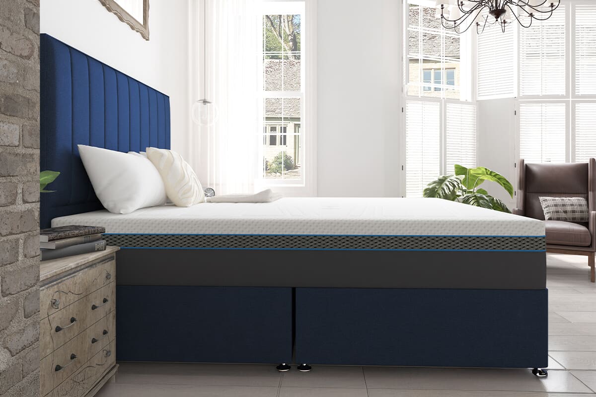 Side-on view of the MLILY summit cool gel mattress on a dark blue divan bed in a light bedroom.