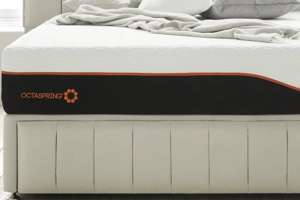 Cropped image of the end of the dormeo octaspring tribrid mattress on a beige divan bed.