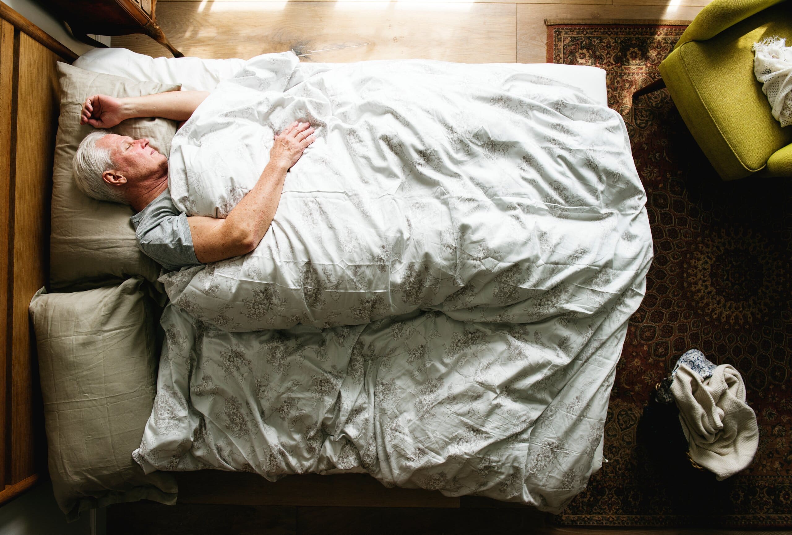 Top view of an older man sleeping on his side in bed. Sleeping position optimised for breathing.