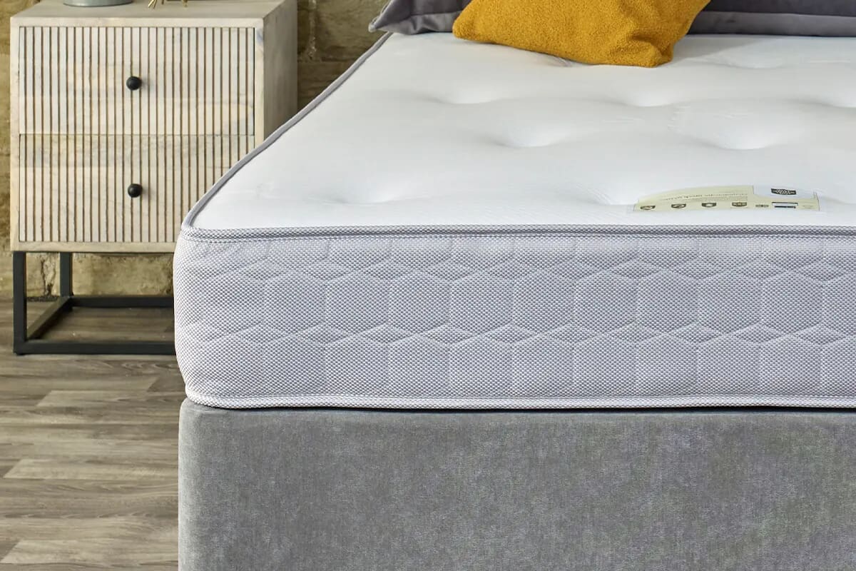 Close up view of an open coil mattress on a divan bed base.