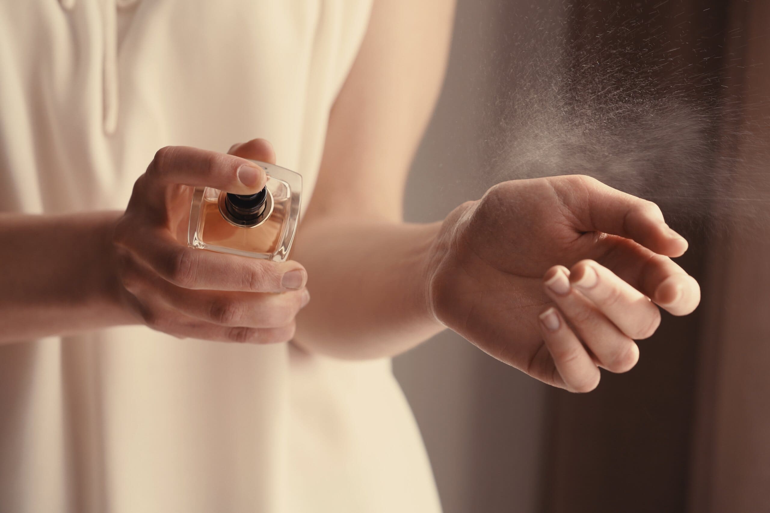 Close-up of a woman's wrist spraying perfume.