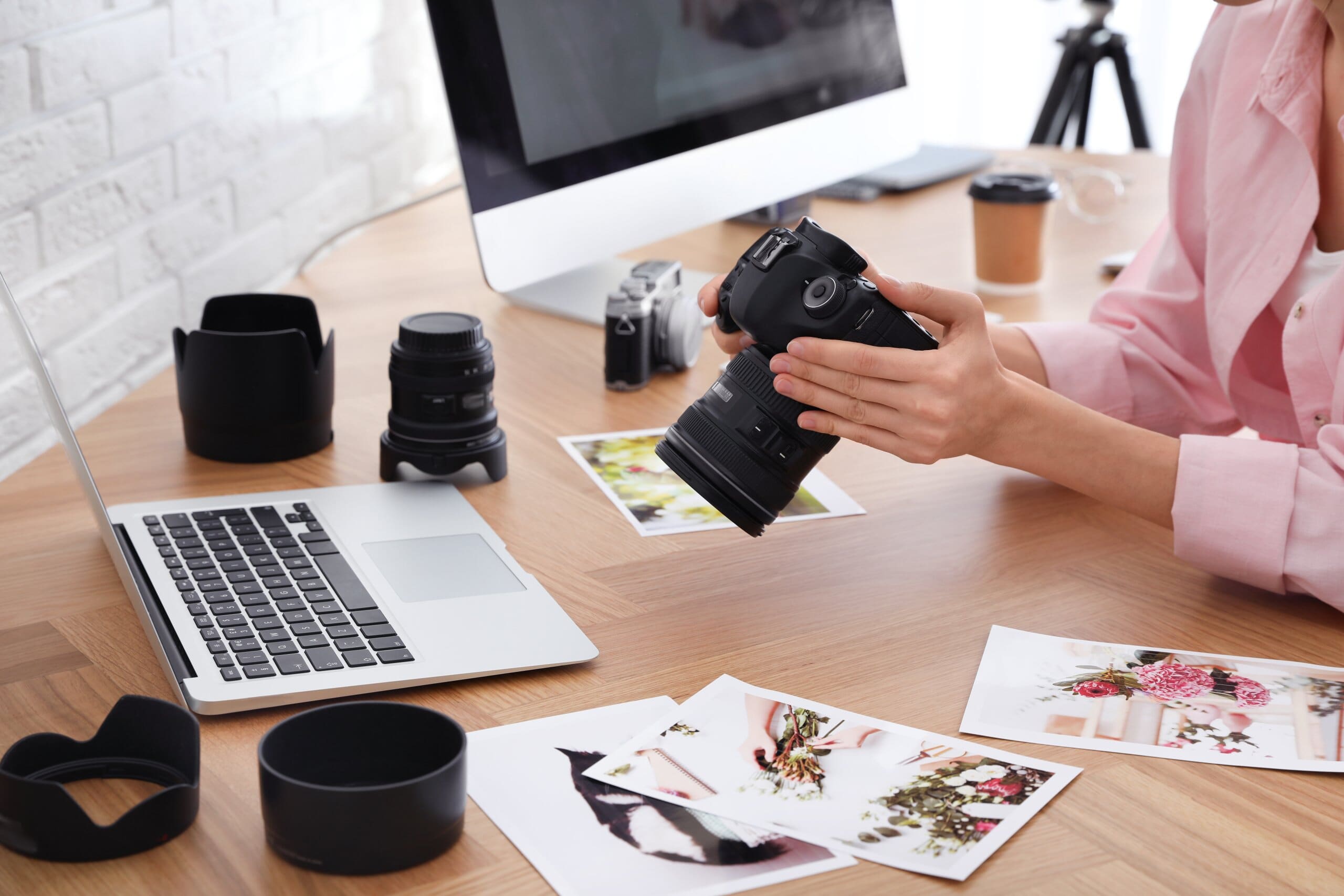 Woman holding camera at desk, looking through photos.