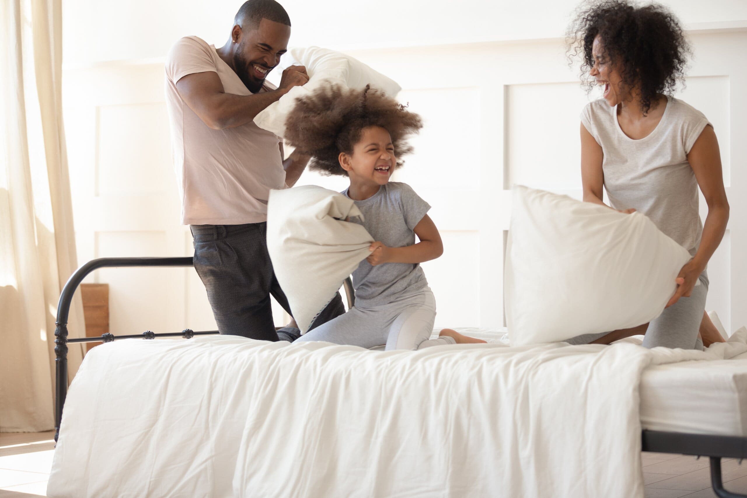 Happy family having a pillow fight on a bed.