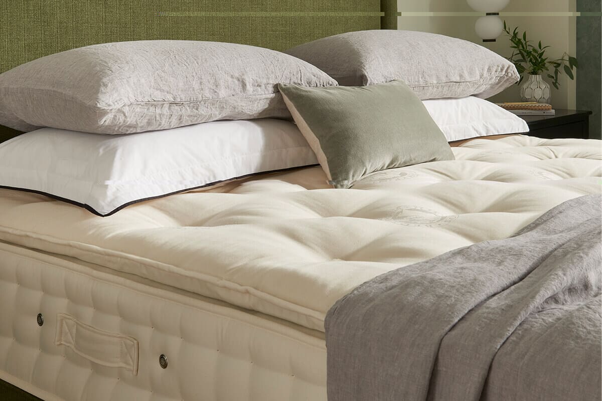 Close up of the Hypnos Pillow Top Luxe mattress with white and grey bedding.