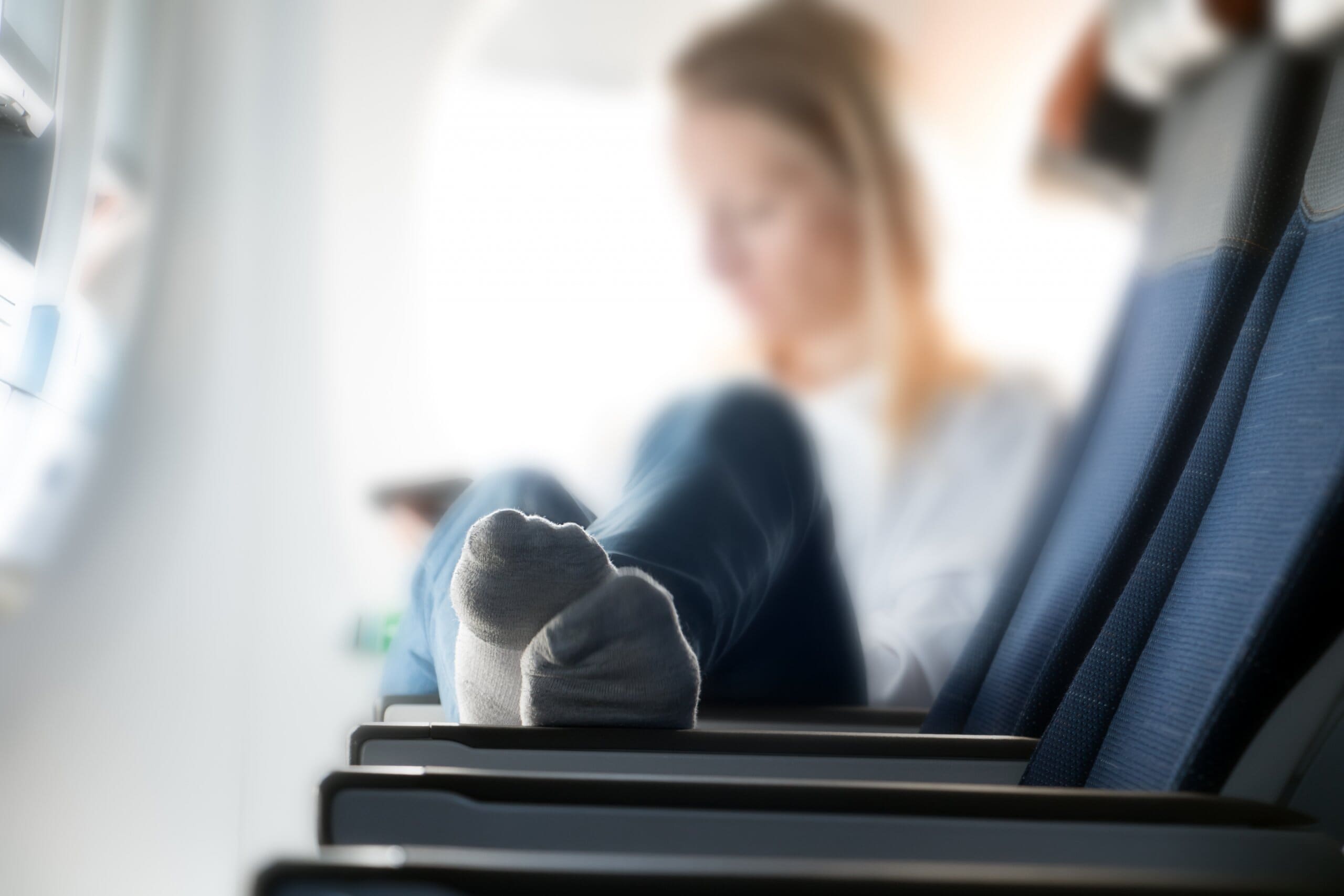 Woman sat on plane stretches out with socks on.