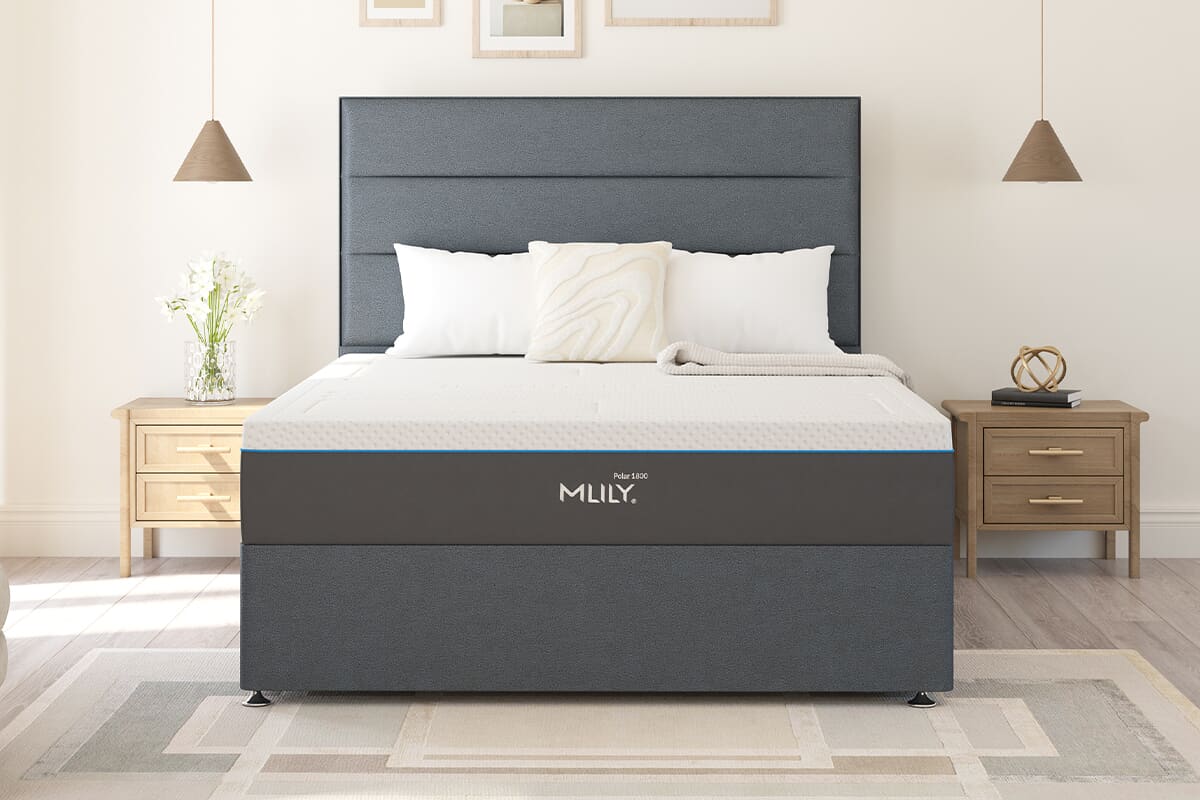 Front on image of the MLILY Polar mattress on a dark grey divan bed in a brightly lit bedroom setting.