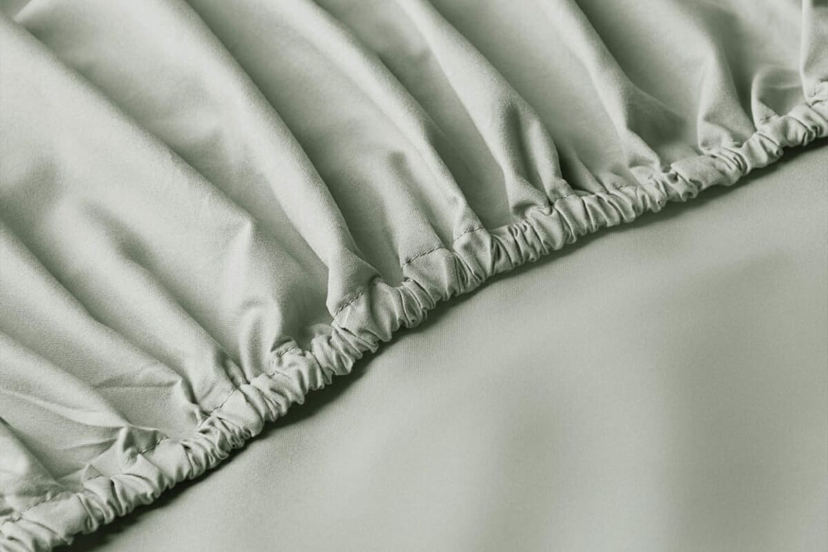 Close up of a soft sage coloured bed sheet with fitted sides.