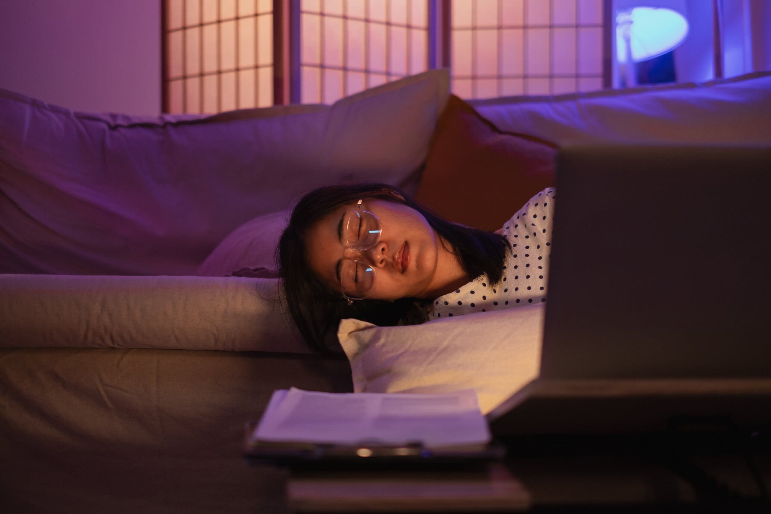 Young female freelancer asleep at her laptop, working during the night.