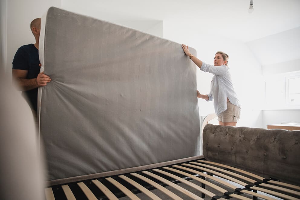 Couple holding a mattress ready to put on a bed frame