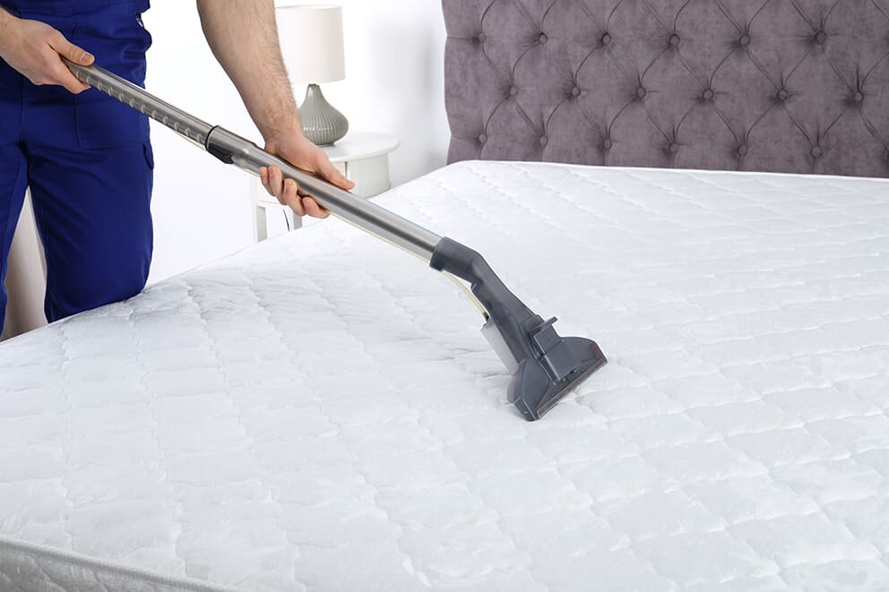 Man vacuuming a mattress 