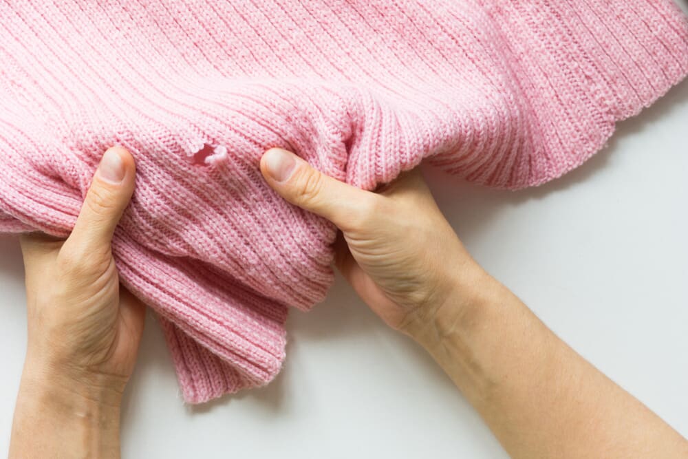 A pink jumper with a hole caused by bugs. 