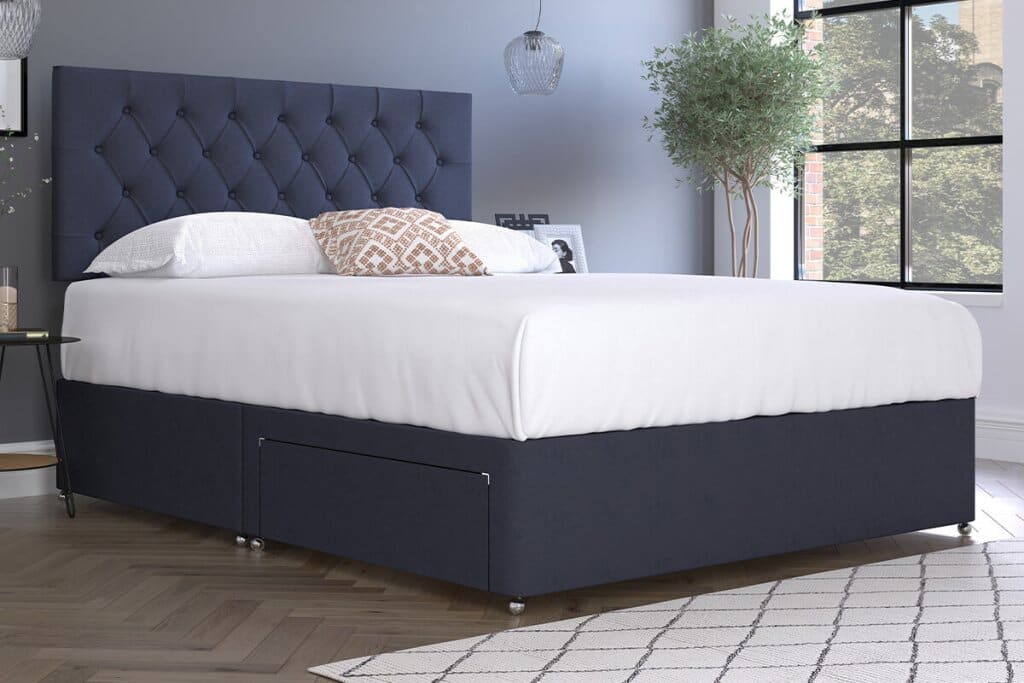 Image of a dressed signature luxury divan with dark blue upholstery.